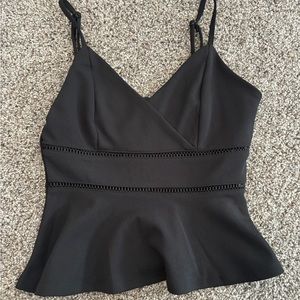 Black dress top with details along the front and ruffled bottom.